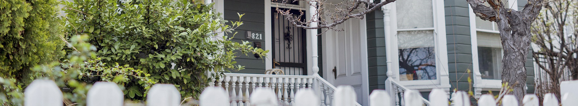 People jogging, using park benches, and with strollers next to a large work of art between the homes.